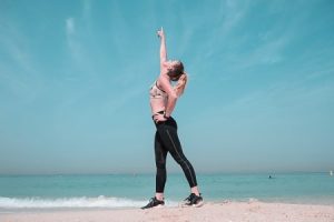 A woman standing on the beach with her arms raised.