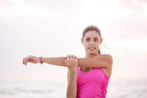 A woman stretching her arm at the beach.