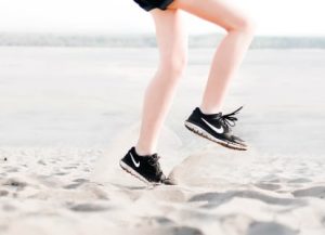 A woman's legs in the sand on a beach.