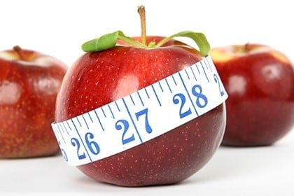 A red apple with a measuring tape on it.