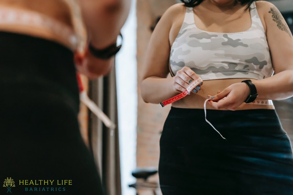 A woman is measuring her waist in a gym.