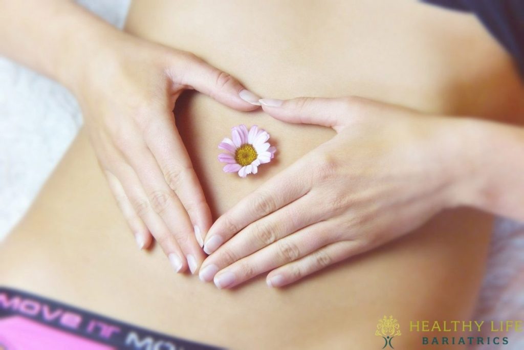 A woman holding a flower on her stomach.