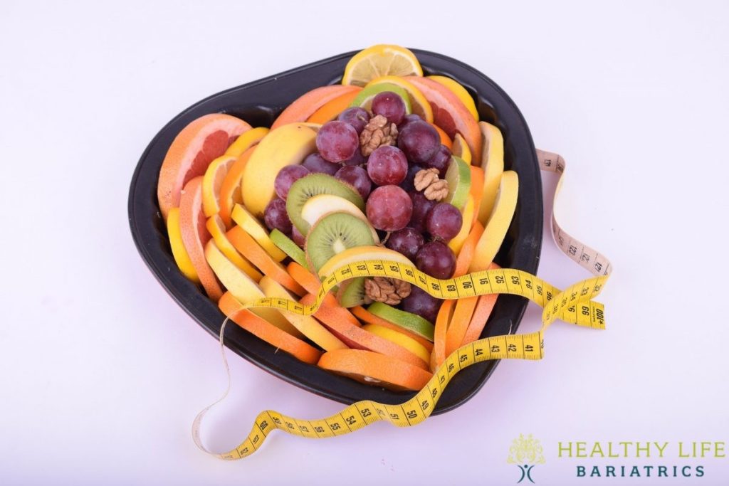 A heart shaped bowl of fruit and measuring tape.