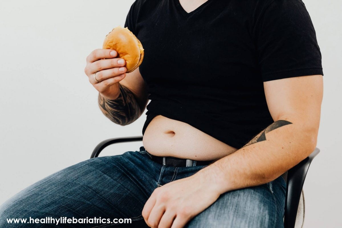 A man sitting in a chair eating a donut.