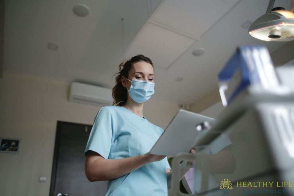 A female dentist wearing a mask and holding a tablet.