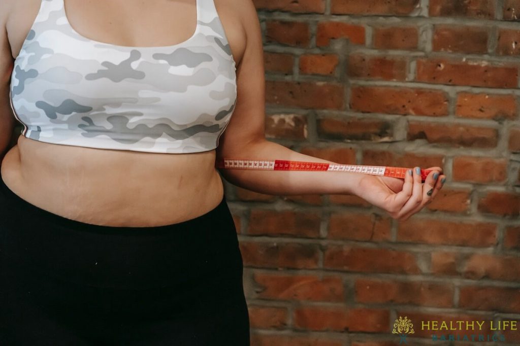 A woman holding a measuring tape in front of a brick wall.