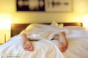 A person's feet laying in a bed with white sheets.