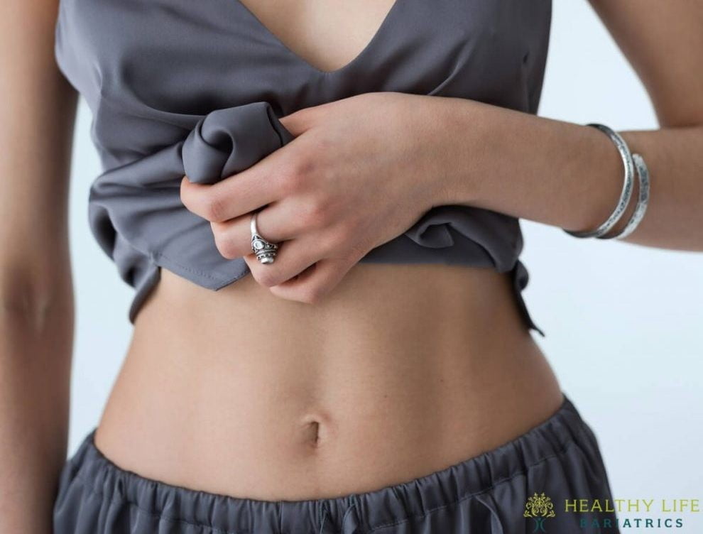 A woman is posing with her hands on her stomach.