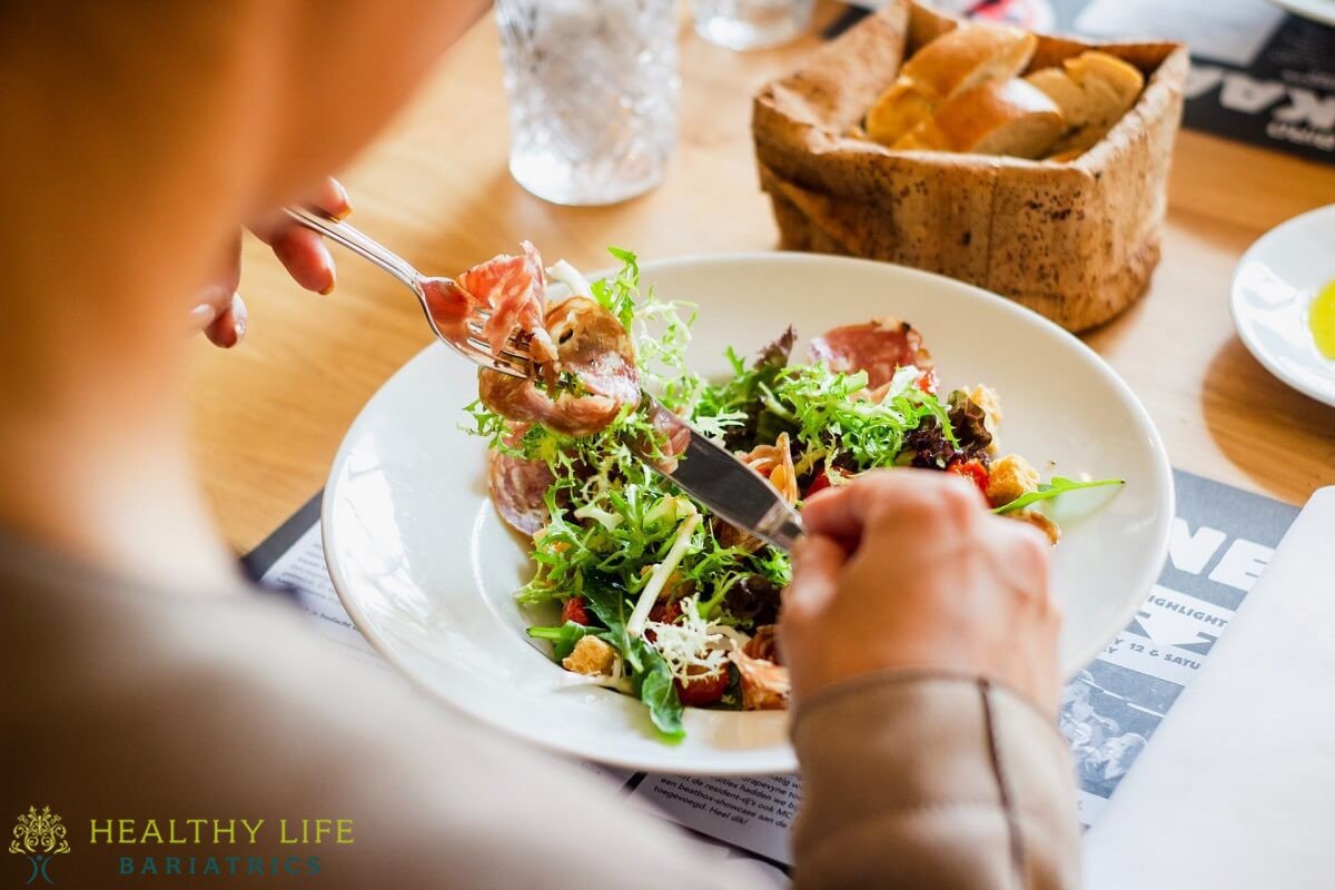 A woman eating a salad at a restaurant.