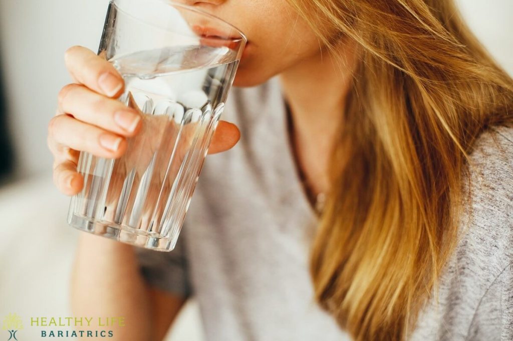 A woman drinking water from a glass.