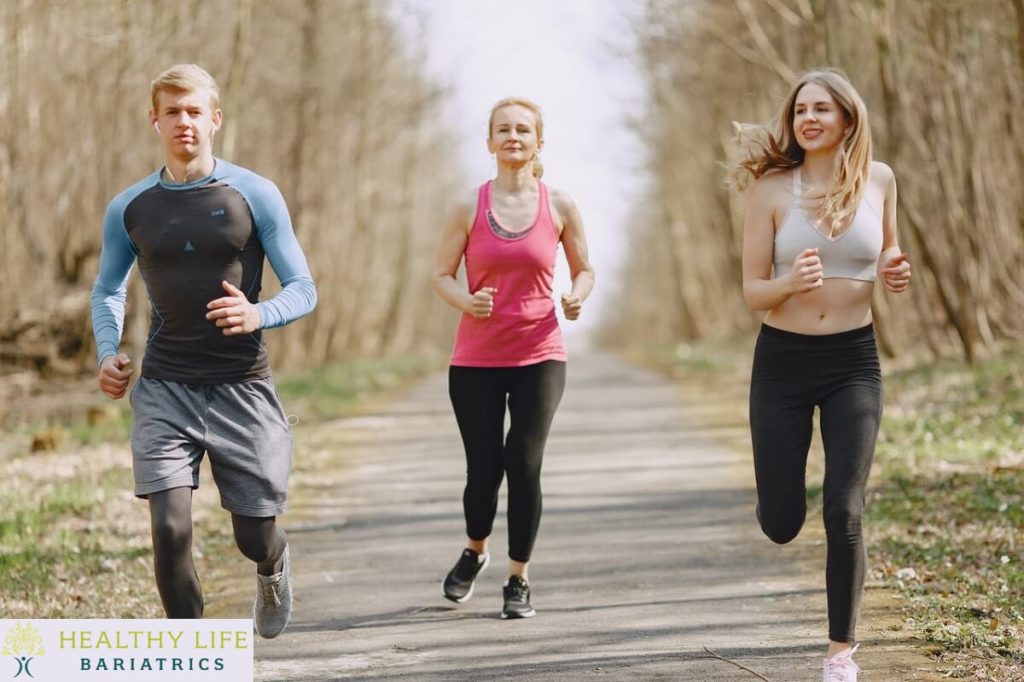 Three people jogging on a path in the woods.