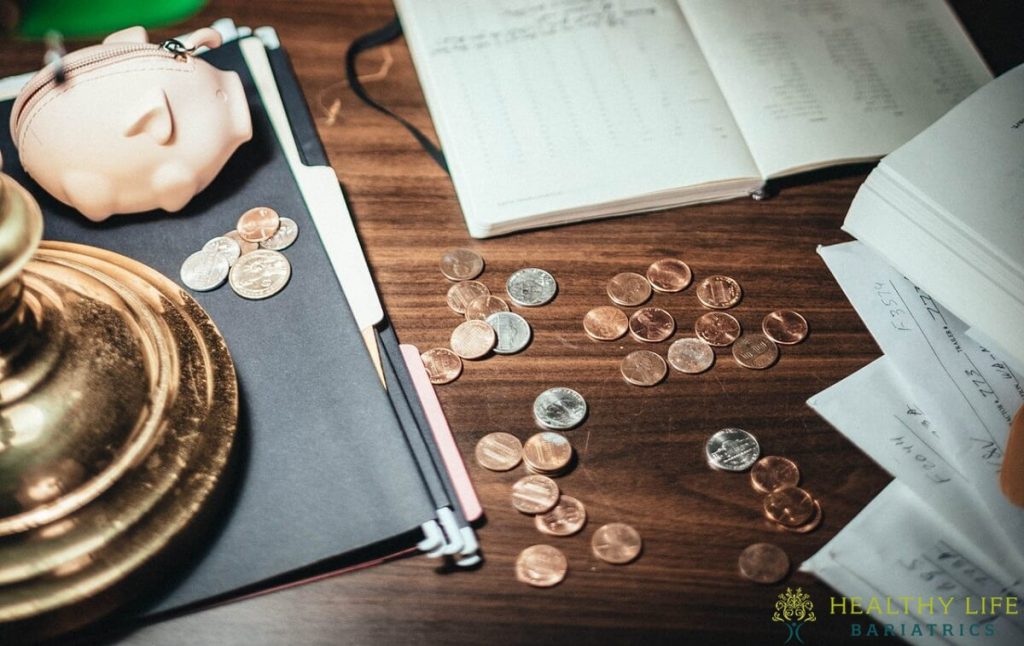 A pile of coins on a desk next to an open book.