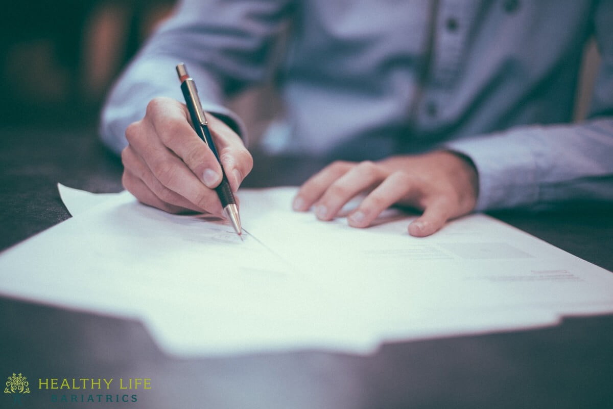 A man signing a document with a pen.