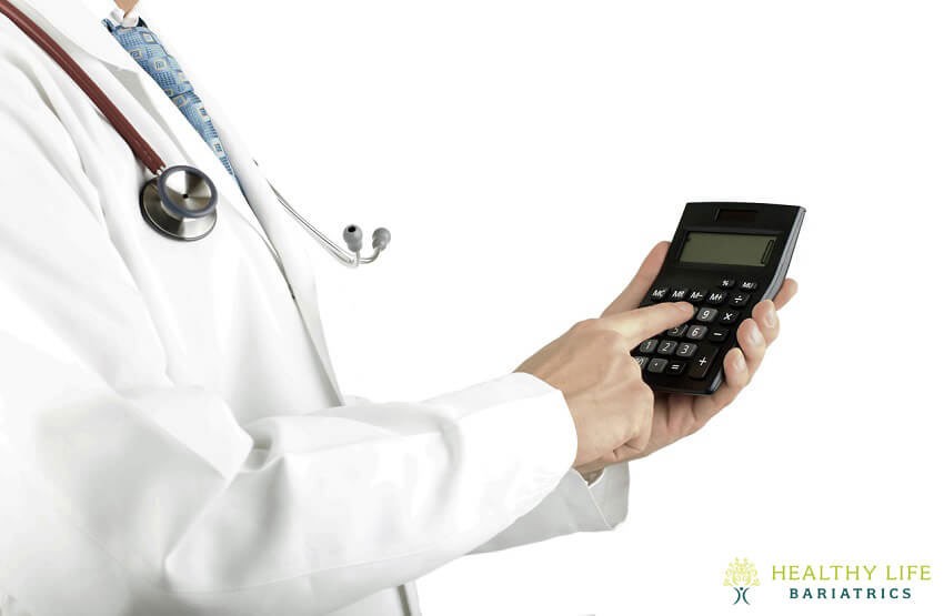 A doctor in a white coat holding a calculator.