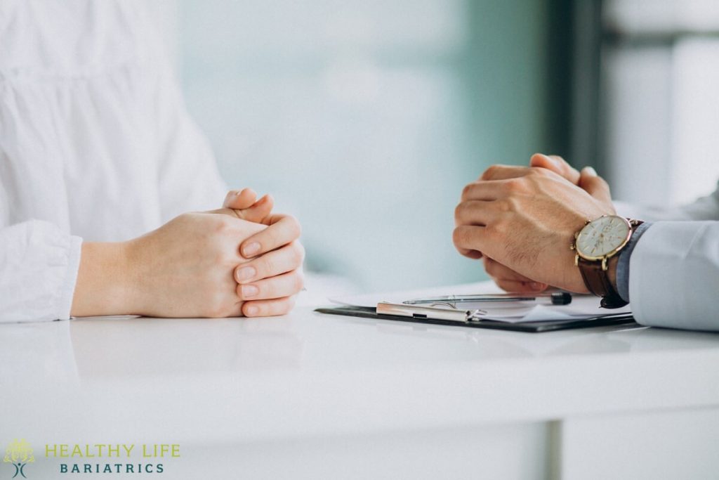 A doctor is talking to a patient at a desk.