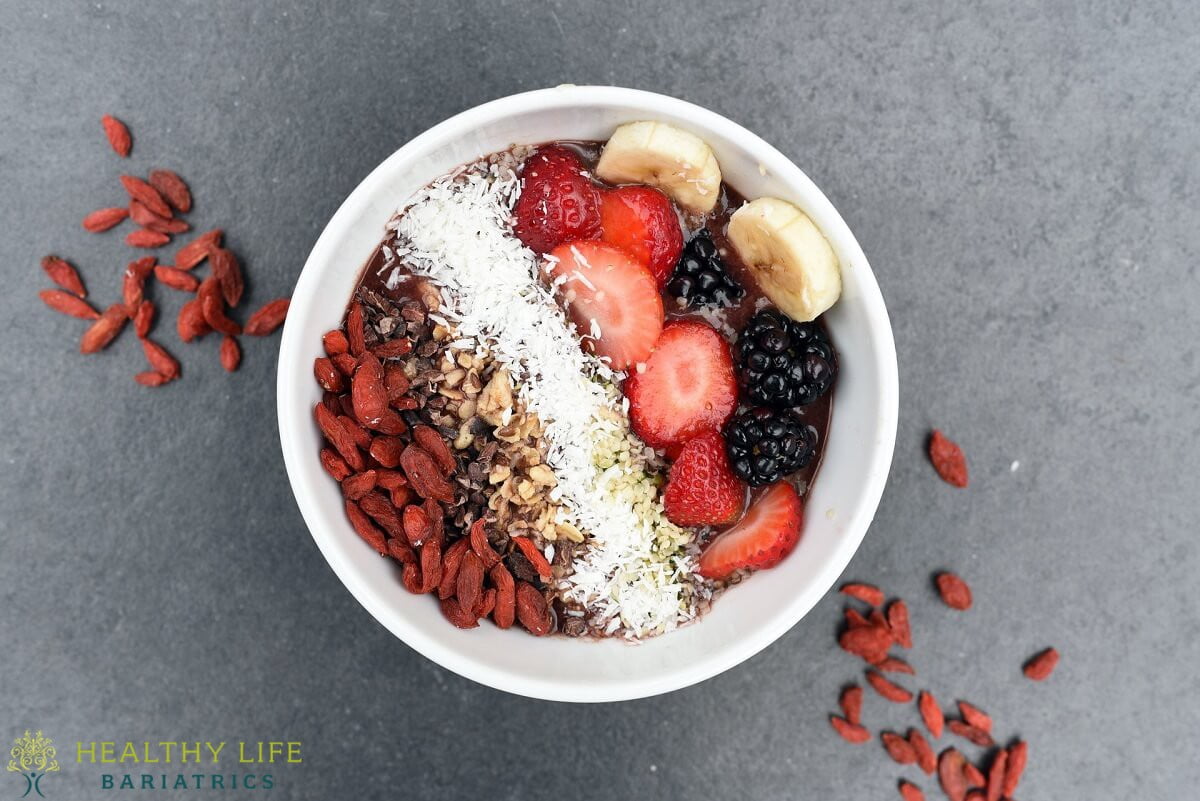 A bowl filled with fruit, nuts and granola.