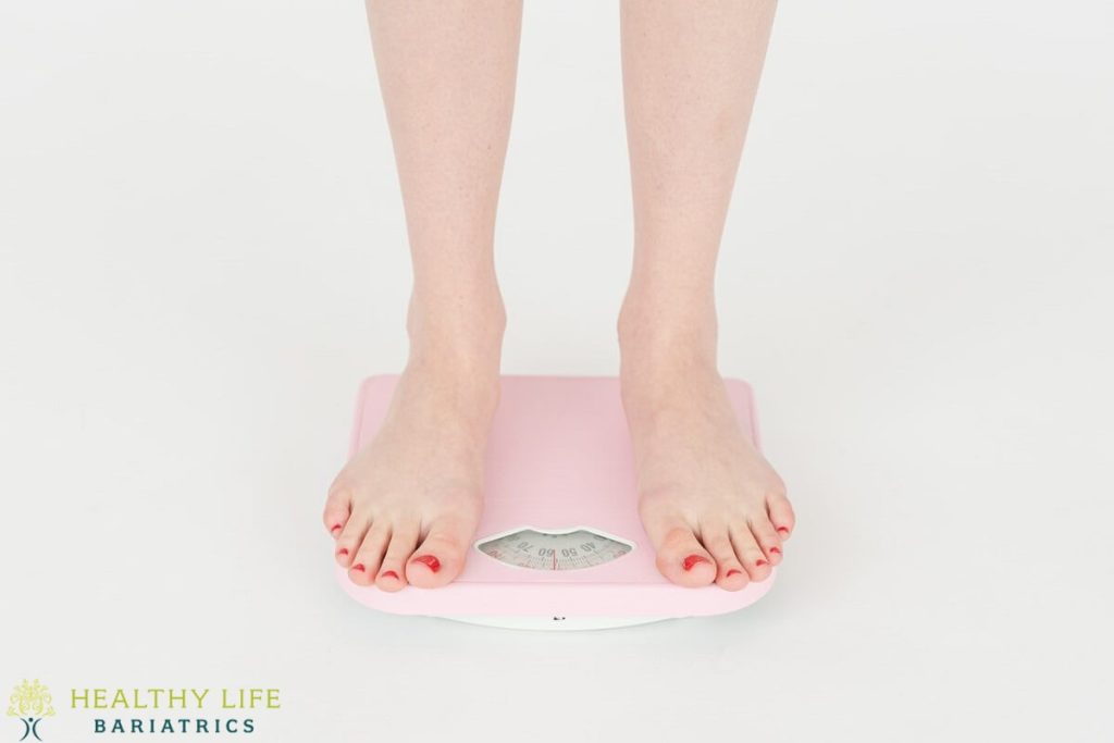 A woman standing on a pink scale.