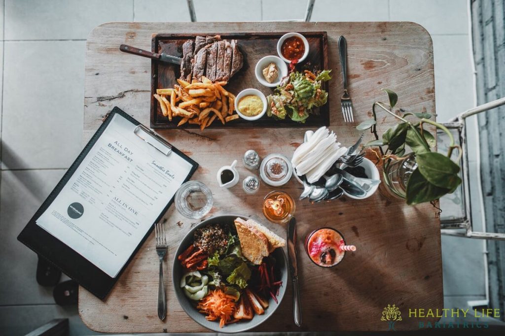 A plate of food and a laptop on a wooden table.