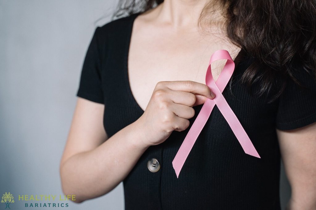 A woman with a pink ribbon on her chest.