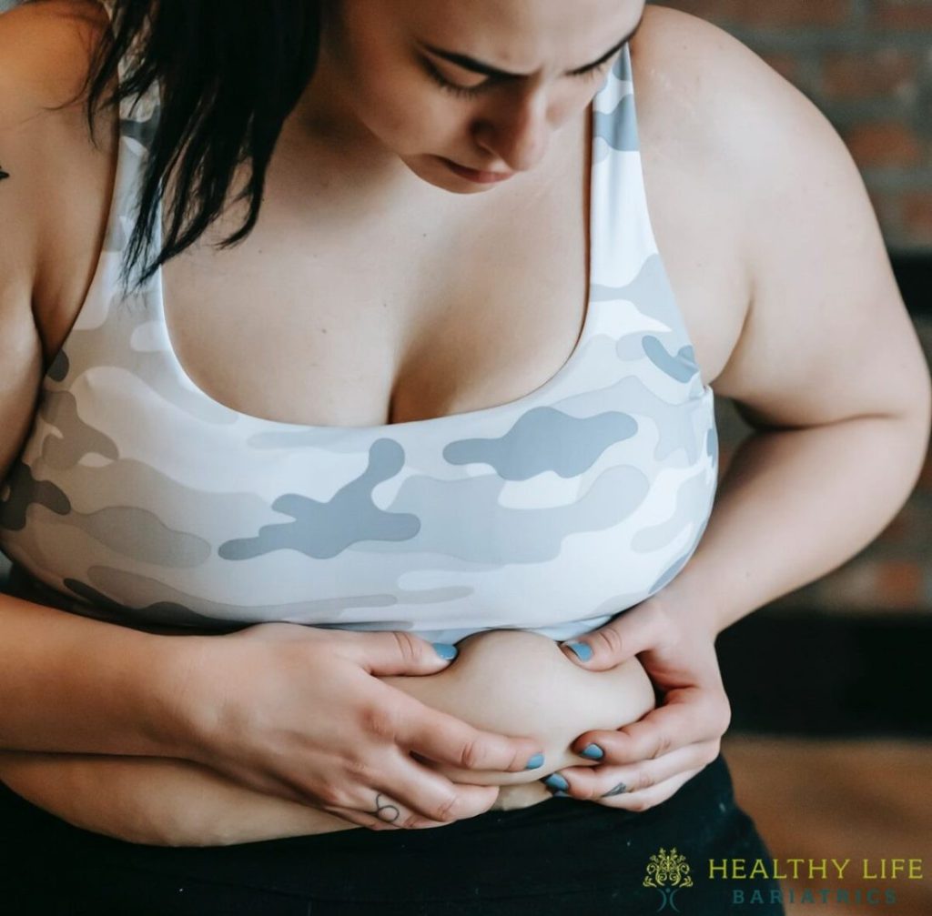 A woman in a camouflage top holding her stomach.