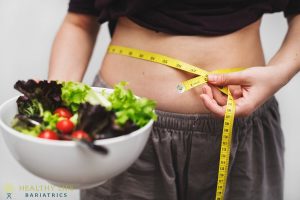 A woman holding a bowl of salad with a measuring tape.