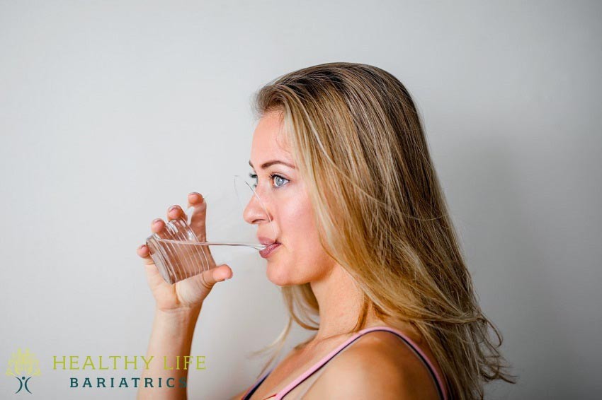 A woman drinking water from a glass.