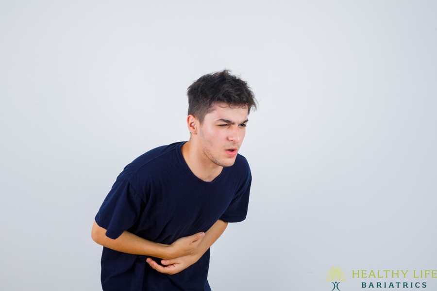 A man with a stomachache is standing in front of a white background.