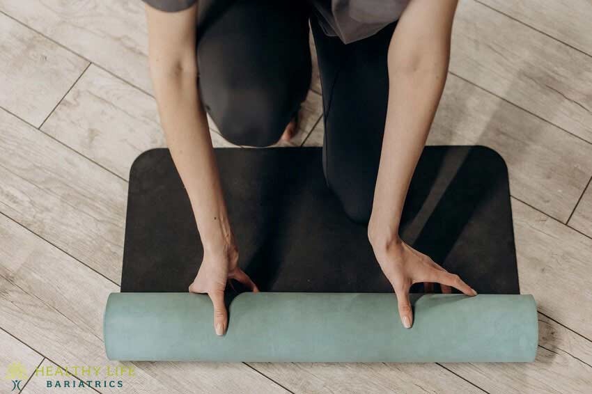 A woman laying on a yoga mat on a wooden floor.