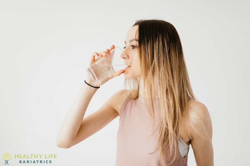 A woman drinking water from a glass.