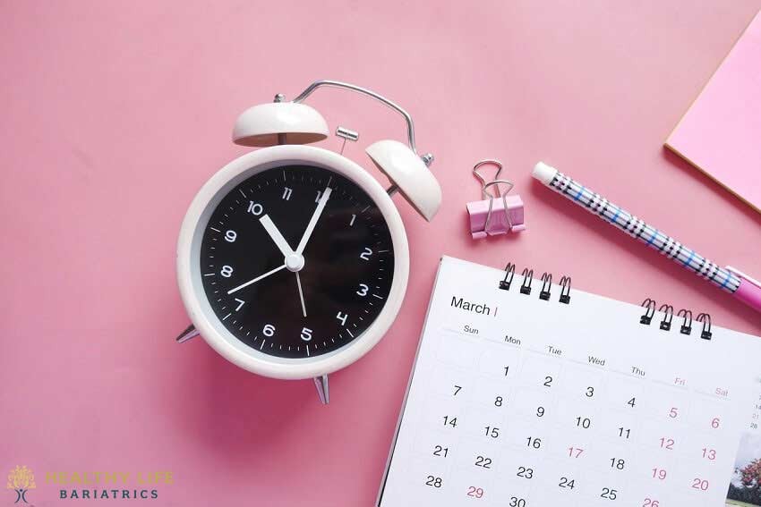 A pink calendar and alarm clock on a pink background.