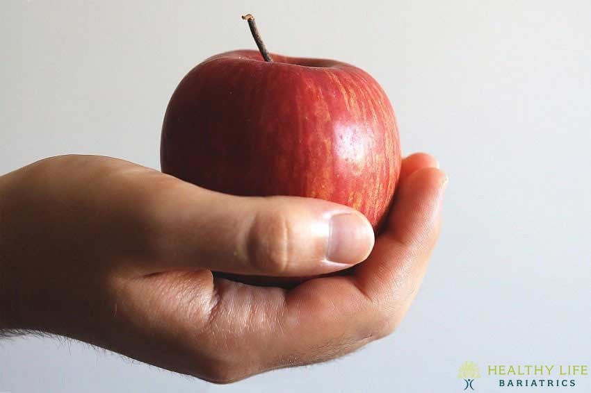 A man's hand holding a red apple.