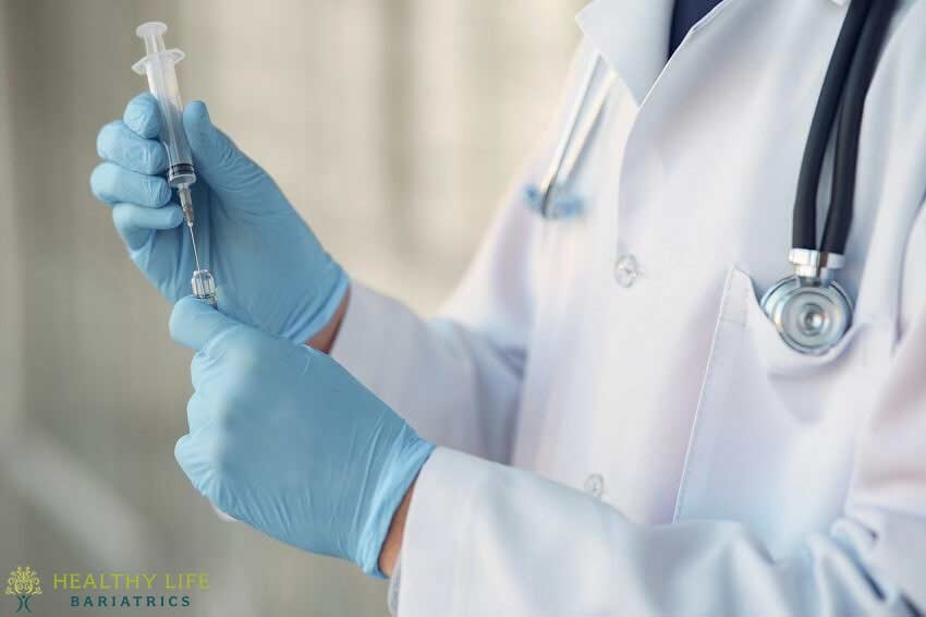 A doctor in blue gloves holding a syringe.