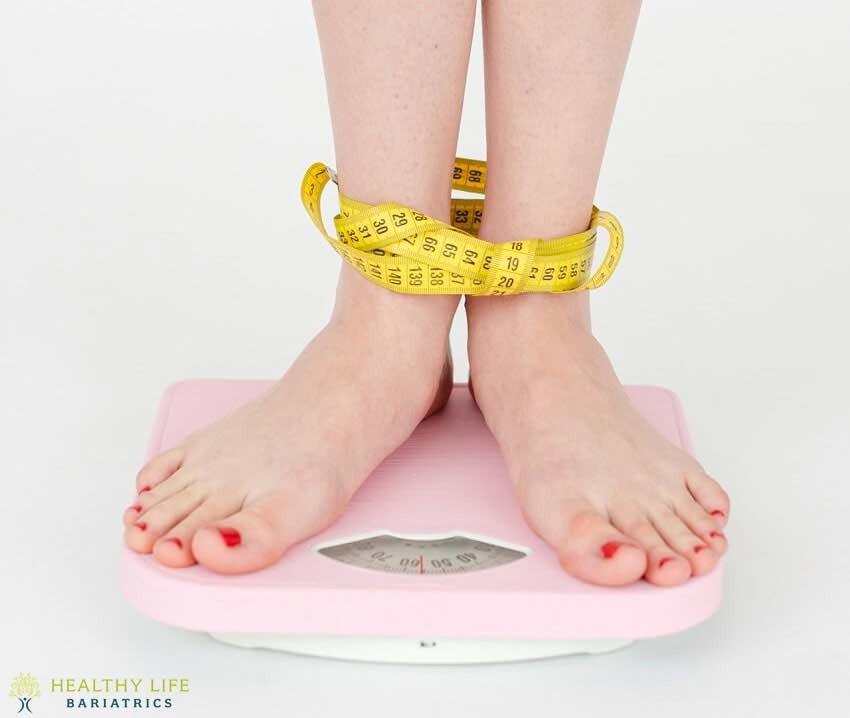 A woman's feet on a pink scale with tape around them.