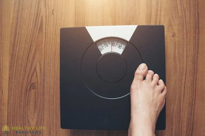 A person's foot standing on a weight scale.