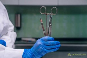 A person in a lab coat holding a pair of scissors.