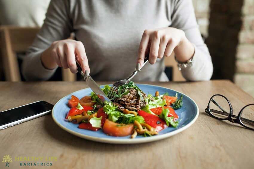 A woman is eating a salad with a fork.