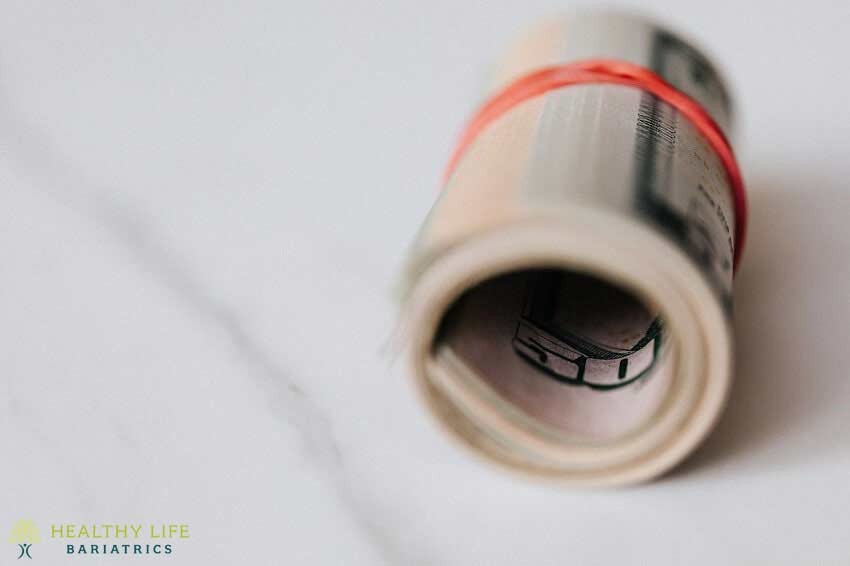 A roll of money with a red ribbon tied around it.