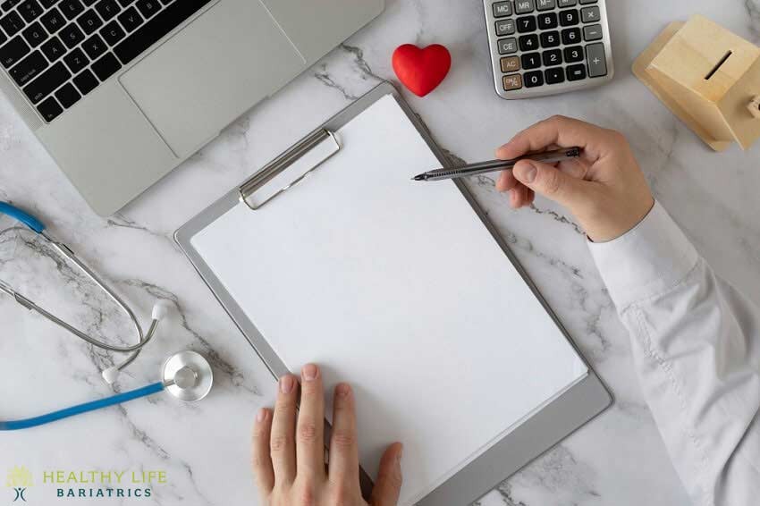 A doctor's hand writing on a clipboard with a heart and stethoscope.