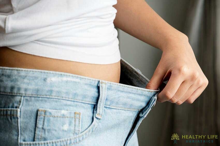 A woman is holding her jeans in her hands.