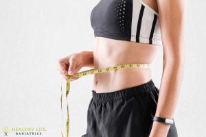 A woman is measuring her waist with a measuring tape.