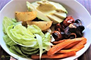 A bowl of vegetables with avocado, lettuce and carrots.