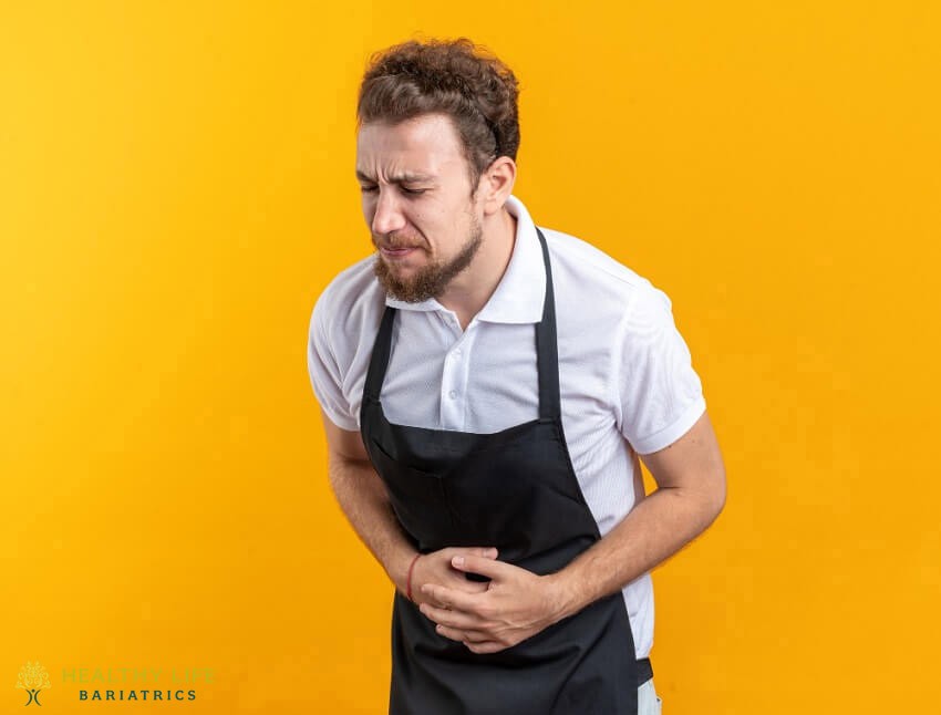 A man in an apron is holding his stomach.