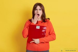 A woman holding a red folder with her mouth open.