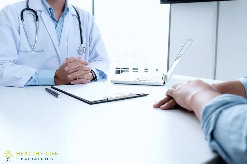 A doctor is talking to a patient at a desk.