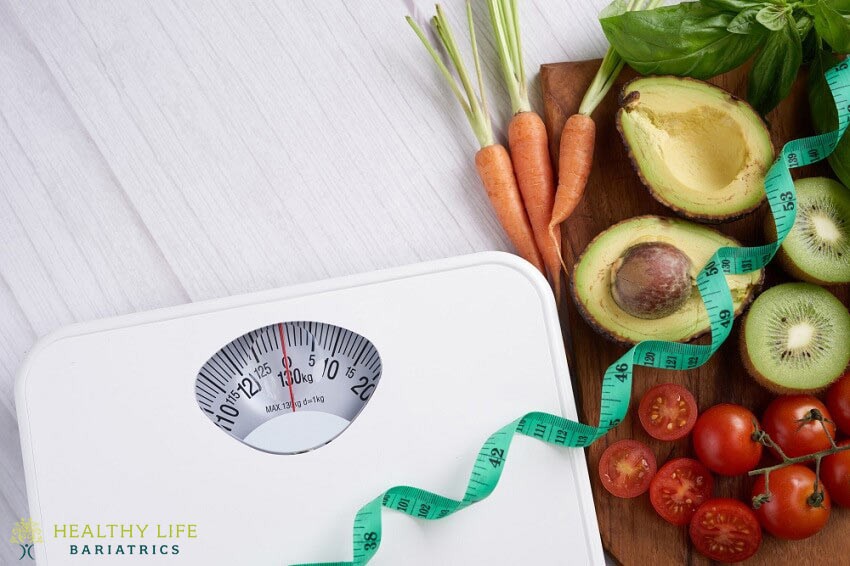 A weight scale with fruits and vegetables next to it.