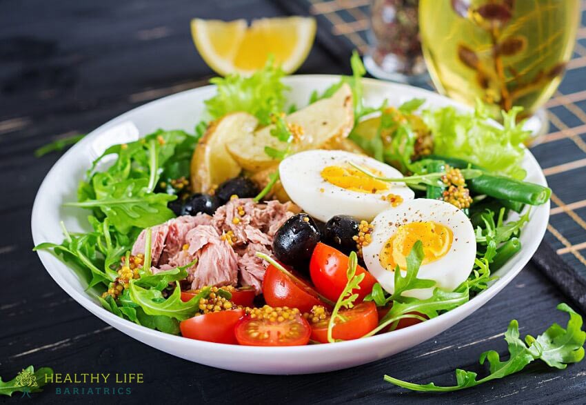 A bowl of salad with tuna, tomatoes and eggs.