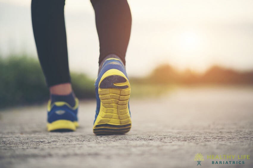 A woman wearing yellow and blue running shoes walking on a path.