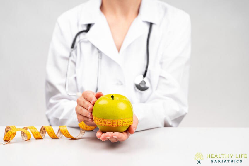 A doctor holding an apple and measuring tape.