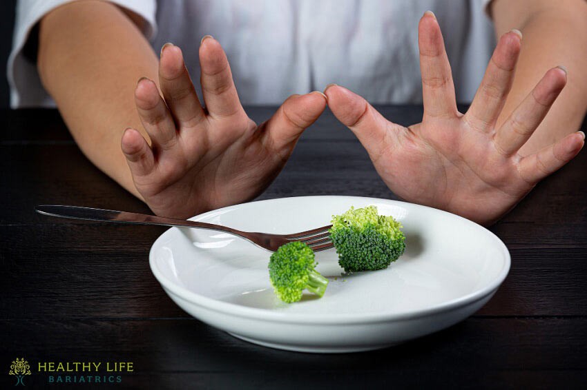 A person holding a plate of broccoli.