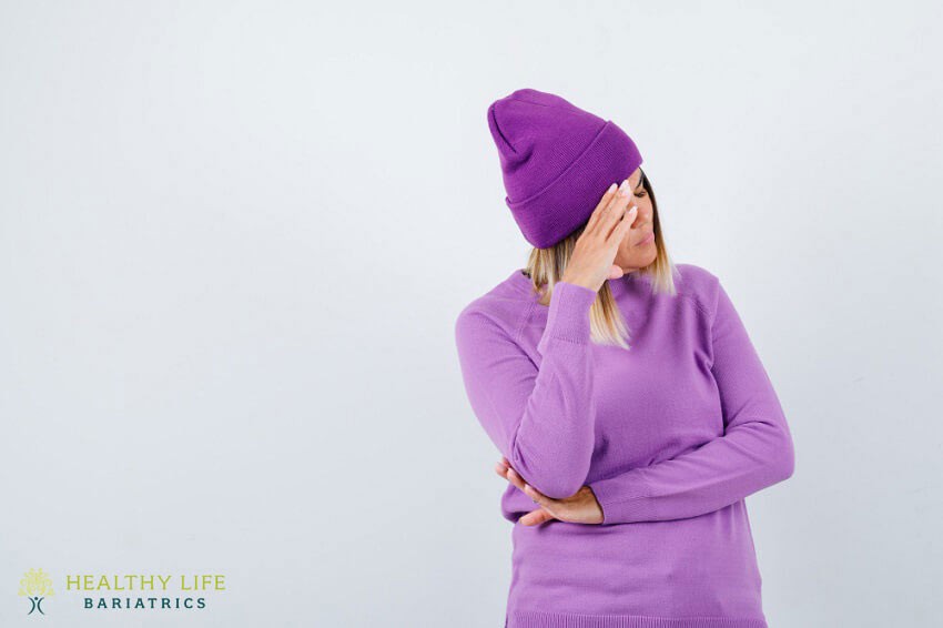 A woman wearing a purple beanie and covering her face.